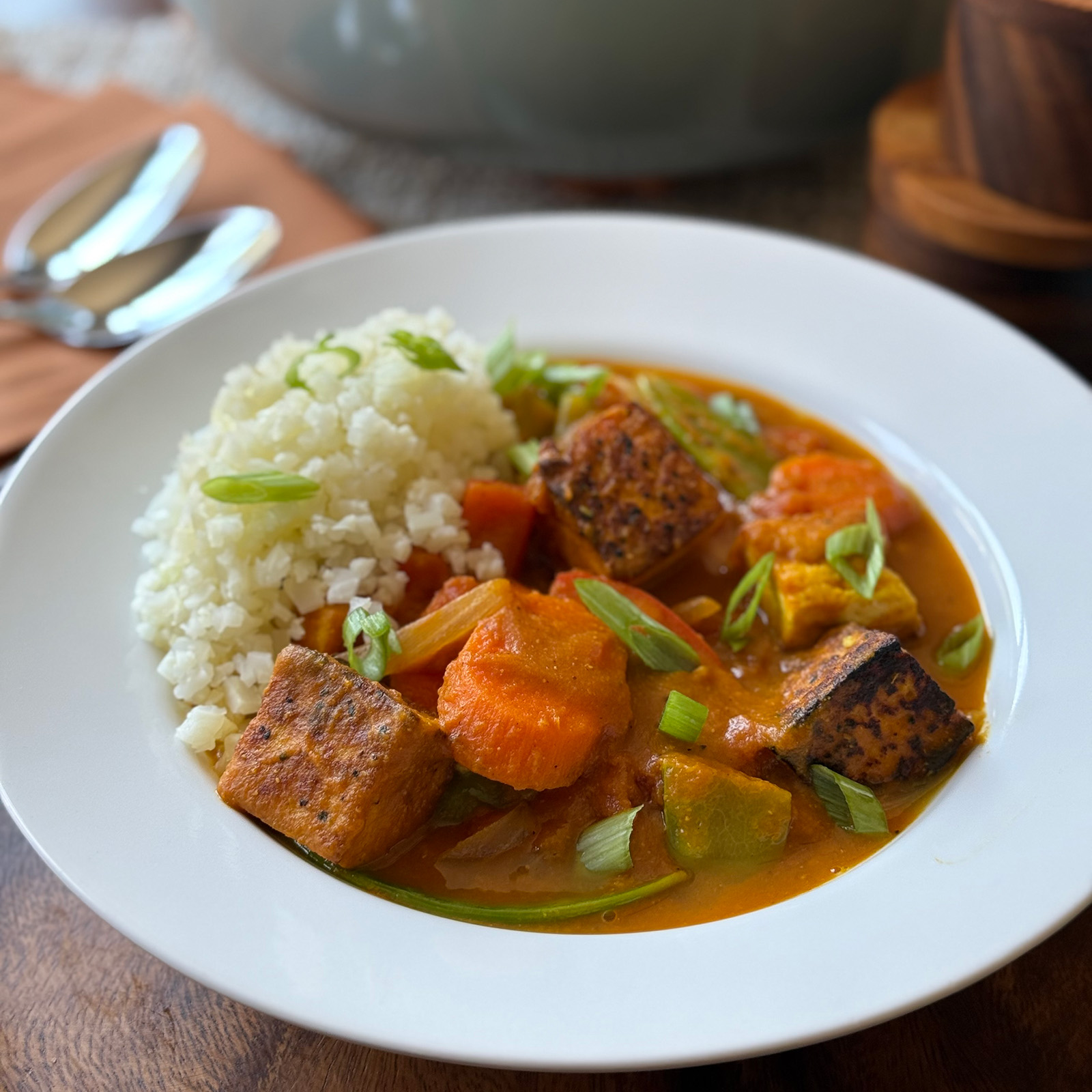 Bowl of pumpkin curry with tofu, snow peas, and red bell pepper served over rice