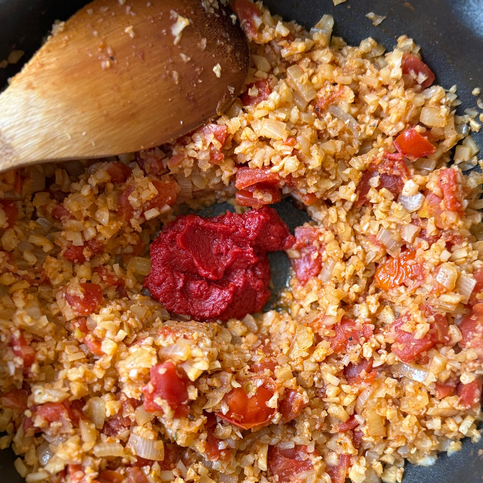 Clearing a well for the tomato paste lets it cook directly against the hot pan for a minute before it's stirred through.