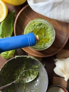 Olive oil being drizzled to the top of Dairy Free Pesto to lock out air and keep it bright green and vibrant