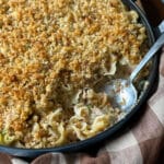 Close-up of baked tuna noodle casserole with a golden breadcrumb topping and a serving spoon