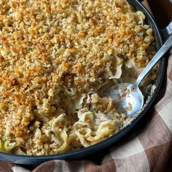 Close-up of baked tuna noodle casserole with a golden breadcrumb topping and a serving spoon
