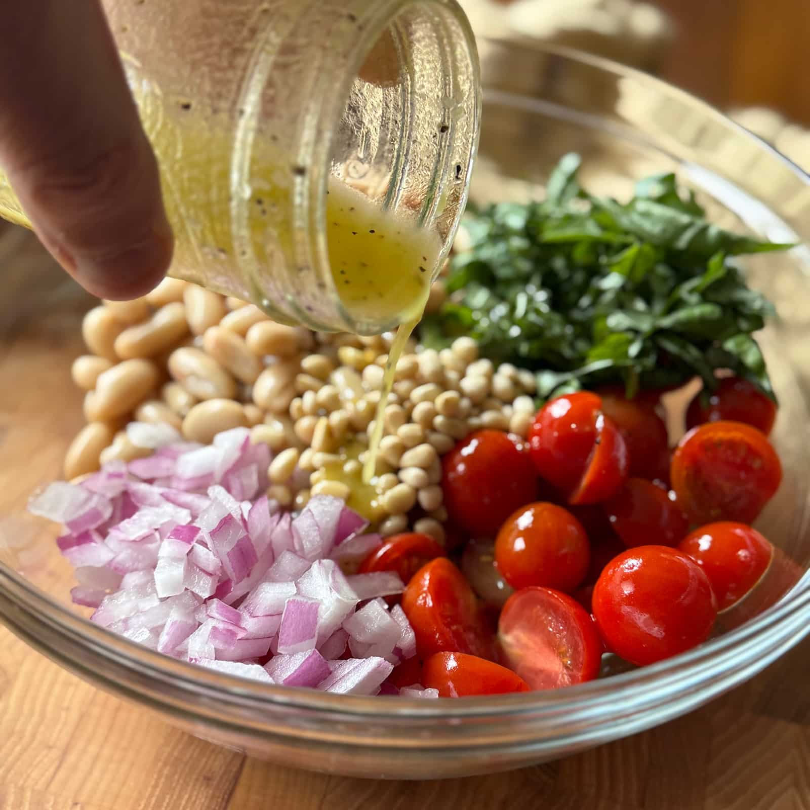 Pouring dressing from a jar into salad bowl