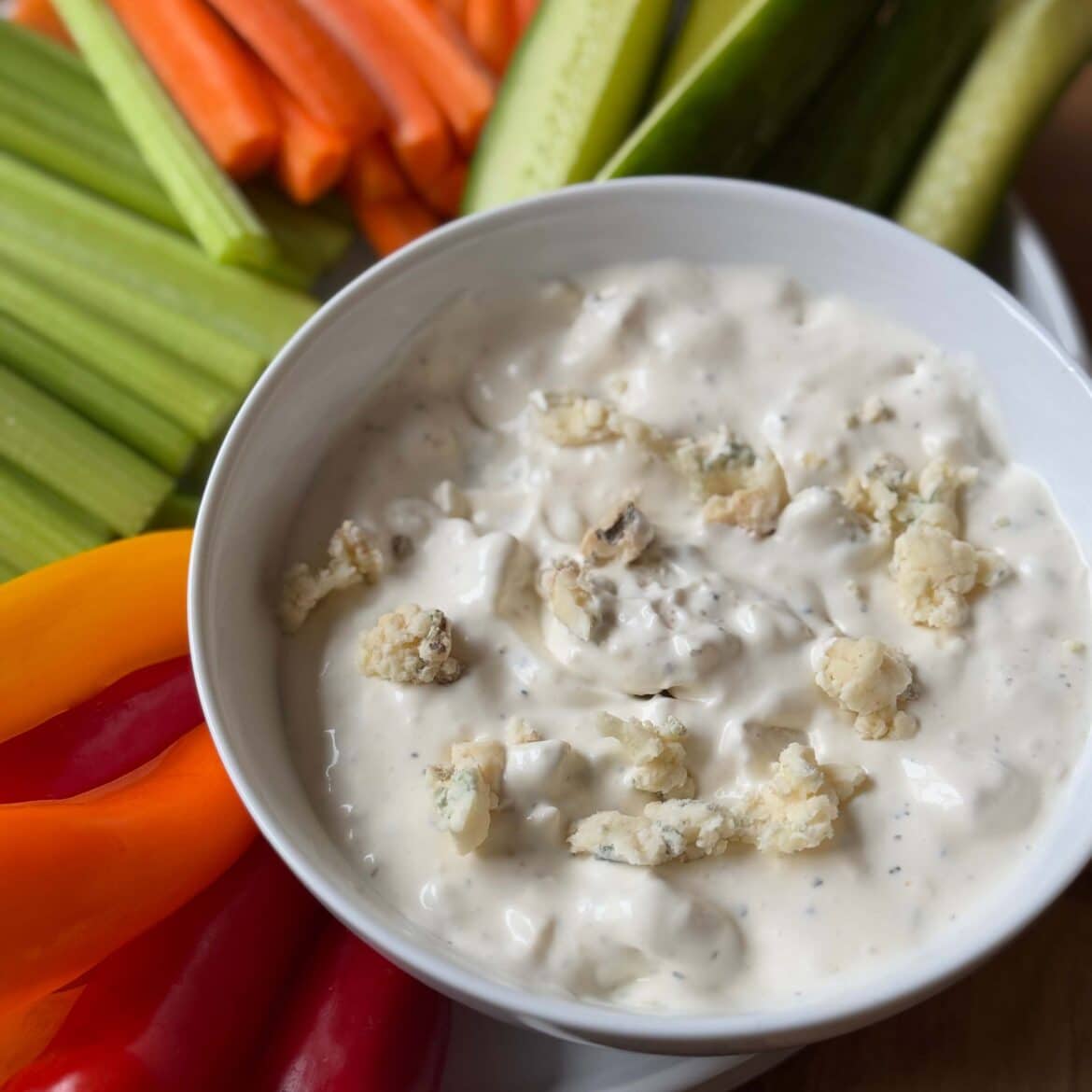 Blue Cheese Dip in a bowl with a side of peppers, celery, carrots and cucumber slices