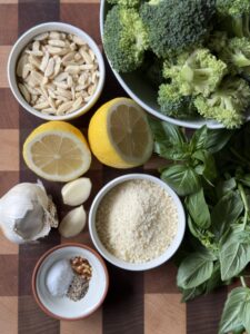 Broccoli Pesto ingredients sitting on a wooden cutting board