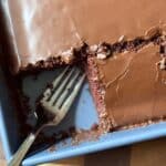 A vegan chocolate cake in a pan with a fork where one slice is missing
