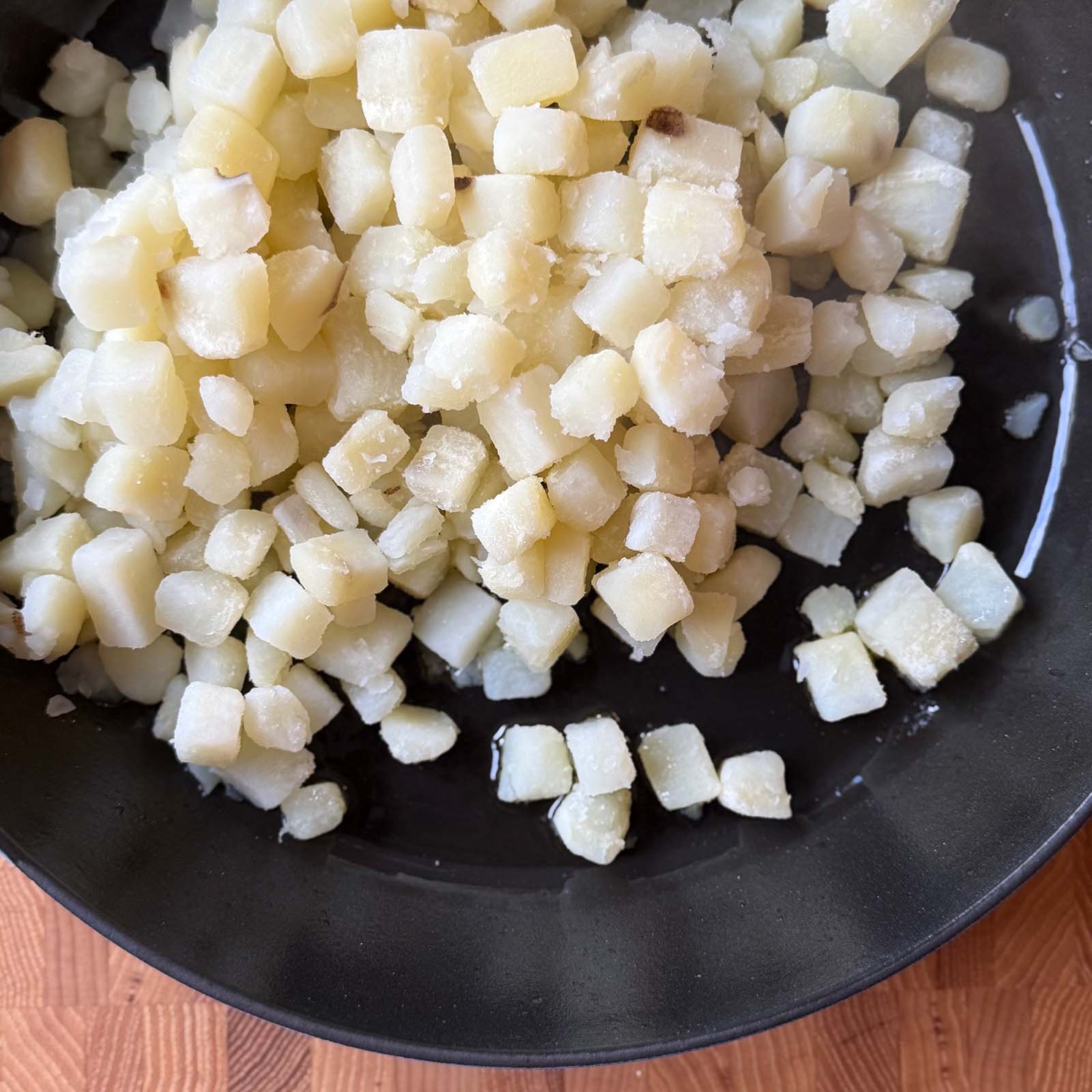 Boiled potatoes added to a skillet