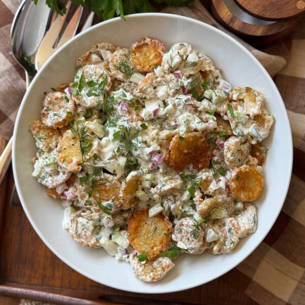 Crispy tater tot potato salad in a large bowl with fresh dill, chopped pickles, celery, and red onion.