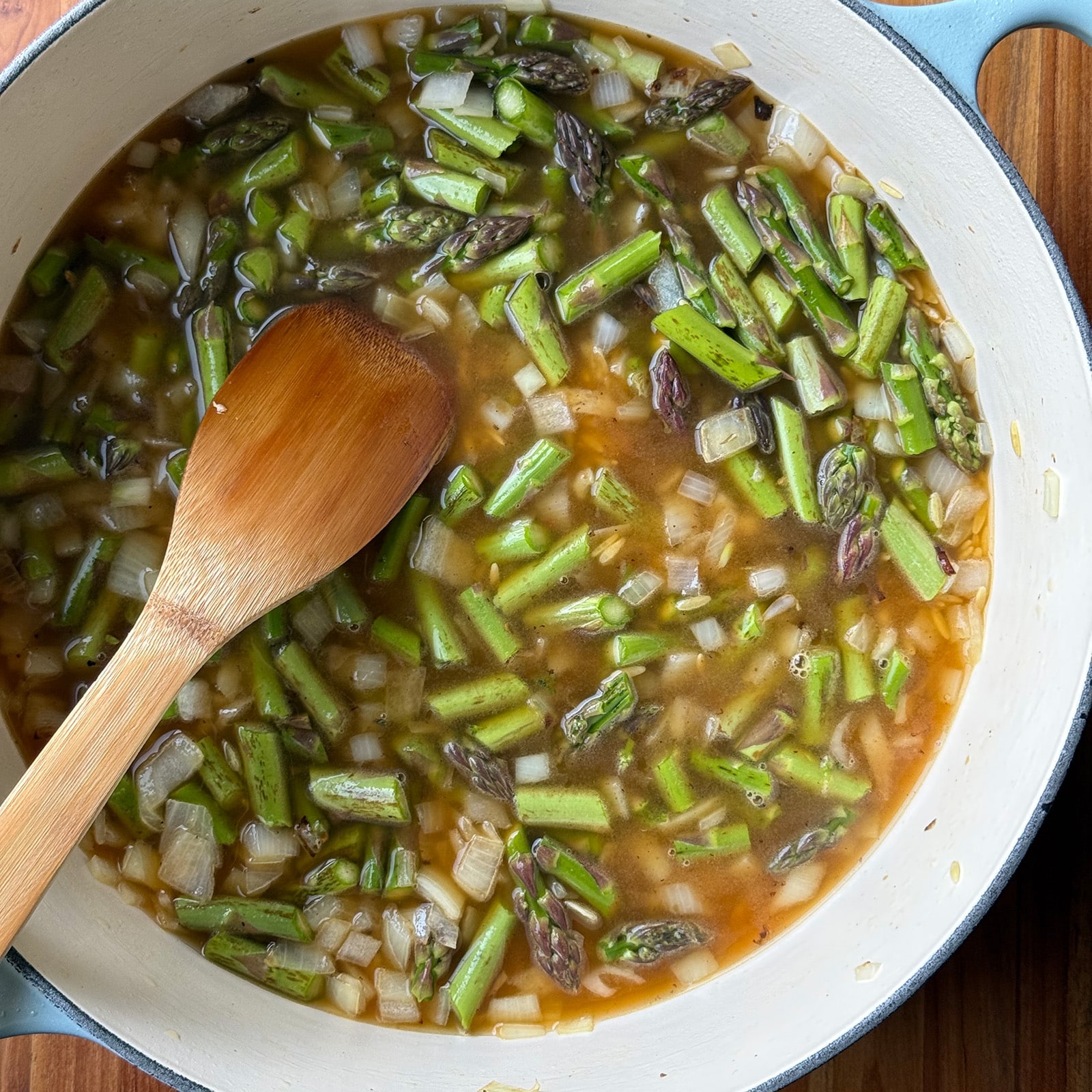 orzo and asparagus with broth in a pot