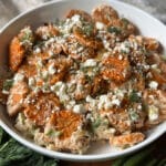 Smashed sweet potato tater tot salad in a white bowl, topped with crumbled feta and fresh dill, with green onions and dill sprigs in the foreground.Smashed sweet potato tater tot salad in a white bowl, topped with crumbled feta and fresh dill, with green onions and dill sprigs in the foreground.