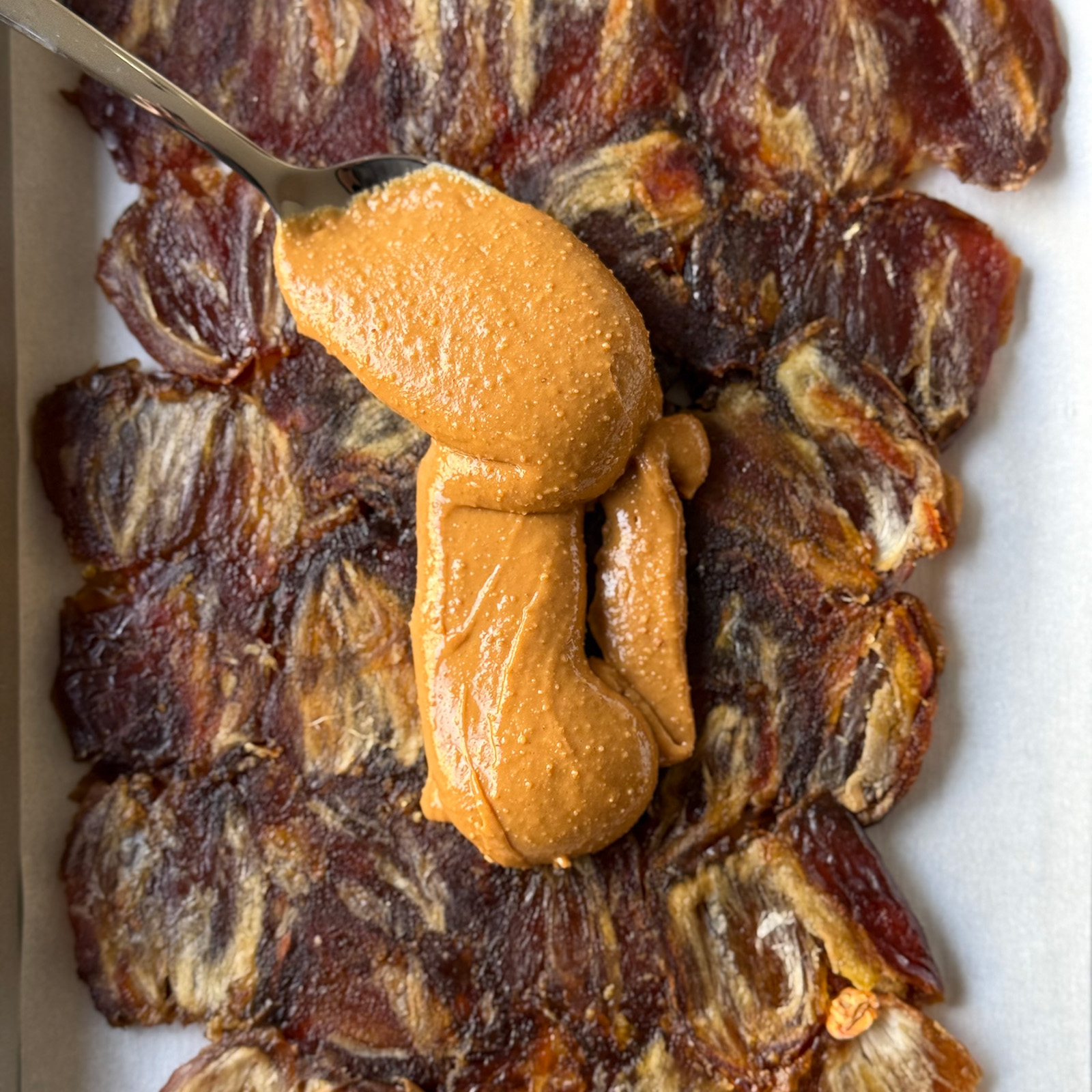Spoonful of creamy peanut butter on a layer of pressed Medjool dates.