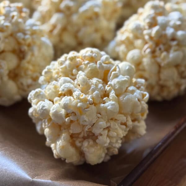 Several Halloween popcorn balls arranged on a baking sheet lined with parchment paper.